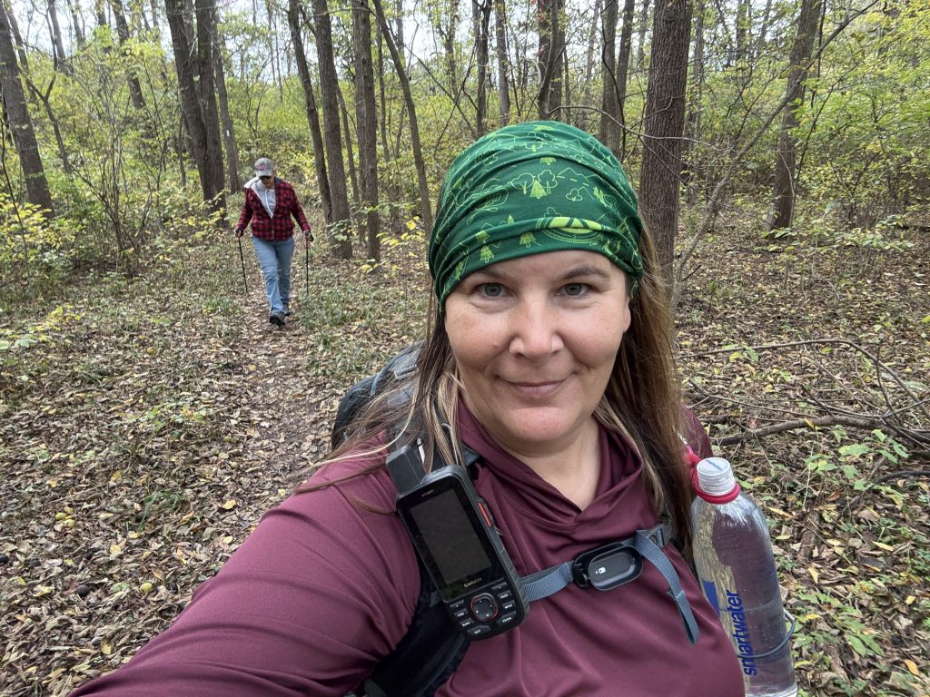 me with my mom in the background looking down as we hike through the woods