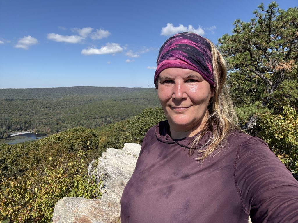 me standing on a rock outcrop overlooking a lake and forest area