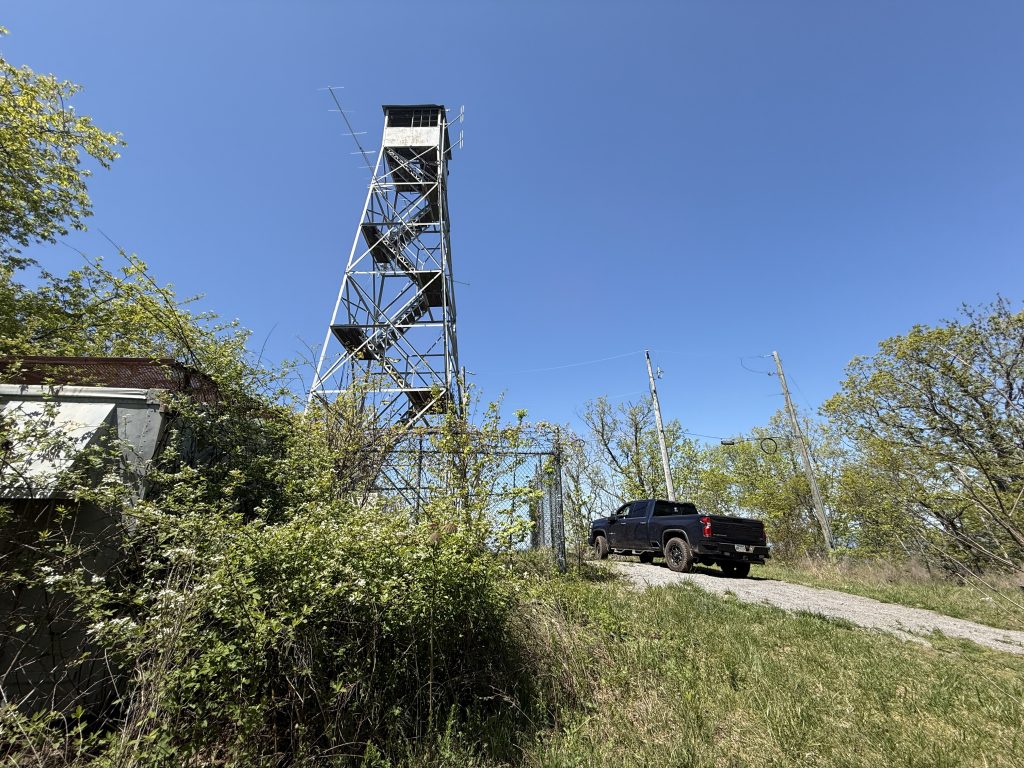 truck next to a dire tower surrounded by grass and trees