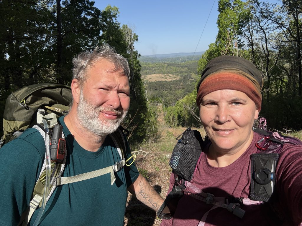 nutty hiker and suspenders standing in a power line clearing with a view 