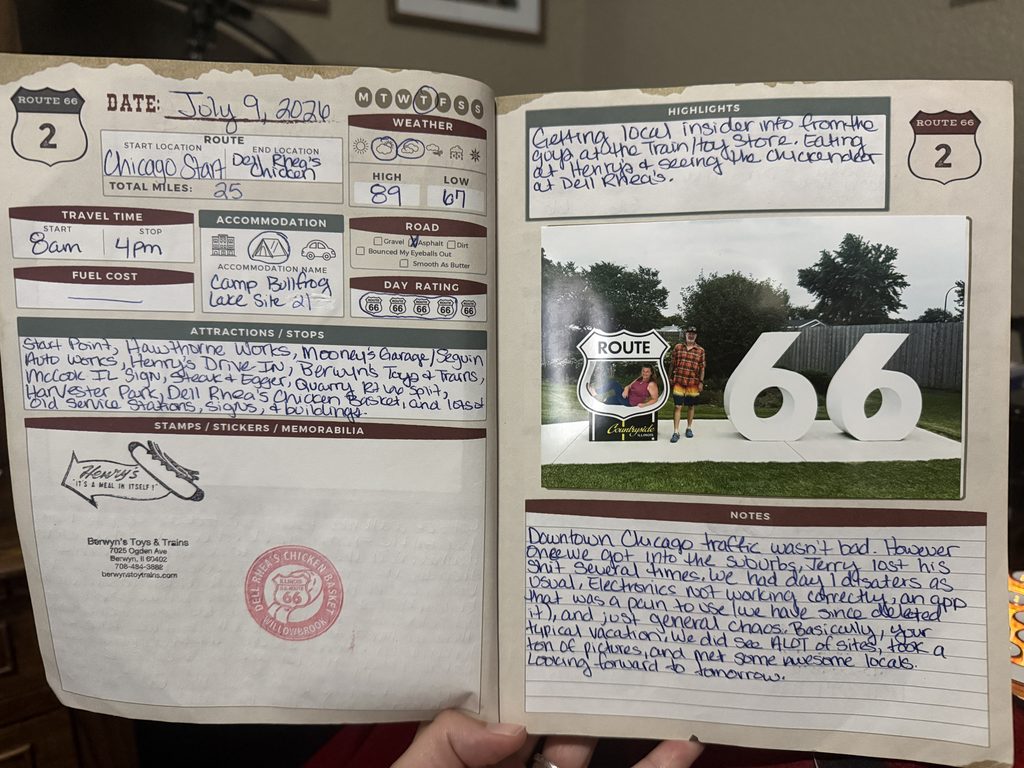 An open travel journal displays handwritten notes, checklists, and a Route 66-themed photograph. The left page includes trip details such as the date (July 9, 2026), start and end locations (Chicago to Dell Rhea's Chicken), weather (high 89°F, low 67°F), stops, and attractions visited, along with stamps from local businesses. The right page features highlights of the day's journey, additional notes recounting travel experiences, and a photo of two people posing with a large Route Burr Ridge sign and giant “66” sculpture in a grassy outdoor setting.